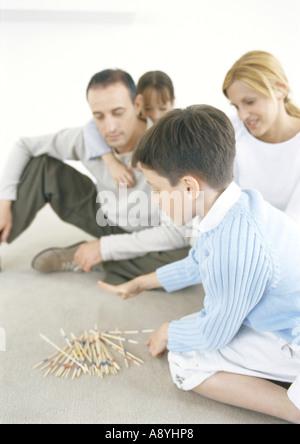 Family playing pick-up-sticks on floor Stock Photo