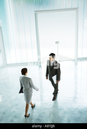 Woman walking to meet businessman in lobby Stock Photo