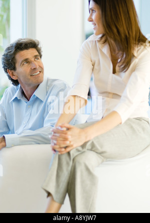 Man sitting on sofa while woman sits on sofa arm Stock Photo