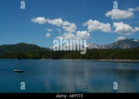 Blue sky with white clouds above a clear lake with a rowing boat Eibsee near Grainau Upper Bavaria Germany Stock Photo