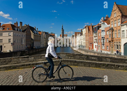 Horizontal wide angle view of traditional canalside gabled buildings and a cyclist in Bruges on a sunny day Stock Photo