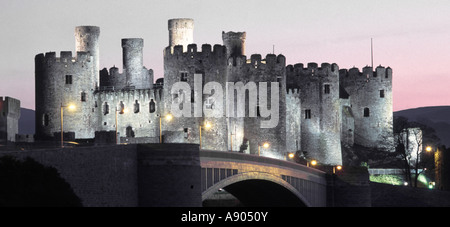 Historical Conwy castle dusk floodlighting illuminating stone walls modern road bridge over River Conwy Snowdonia national park Gwynedd North Wales Stock Photo