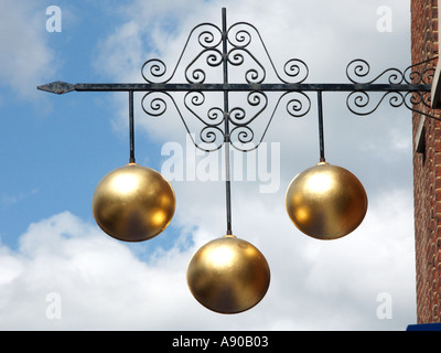 Pawn shop close up of traditional sign of three gold balls above Pawnbroker shop premises supported on ornamental iron bracket England UK Stock Photo