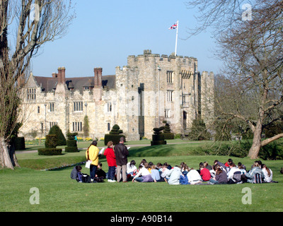 Hever Castle school children group sitting on lawn educational visit & teachers lesson historical Grade I listed building Edenbridge Kent England UK Stock Photo