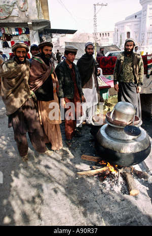 Pakistan NWFP Peshawar Qissa Khawani Bazaar group of Pathan men around pavement cooking fire Stock Photo