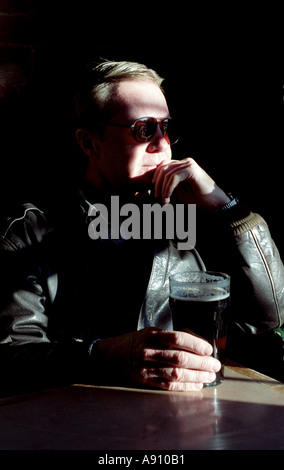 Blond drinking a beer in a pub in the shadows of window light Stock Photo