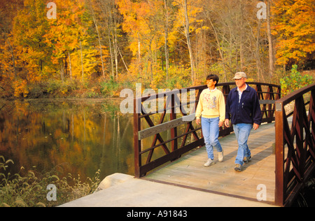 A couple walking over a bridge along a lake in the fall at Kickapoo State Park Illinois Stock Photo