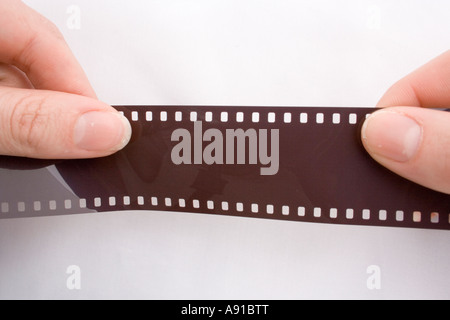 Two hands holding a roll of film negatives, trying to tear it apart against a white background. Stock Photo