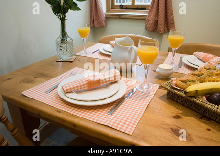 A wooden table laid for breakfast with orange juice Stock Photo