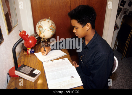 Fifteen year old african american boy doing homework and studying at home. Stock Photo