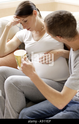 man giving his pregnant partner a cup of tea Stock Photo