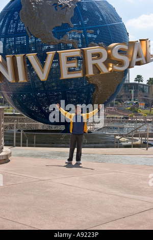 Young Latino tourist poses in front of the Universal Globe, Entrance, Universal Studios, Orlando, Florida Stock Photo