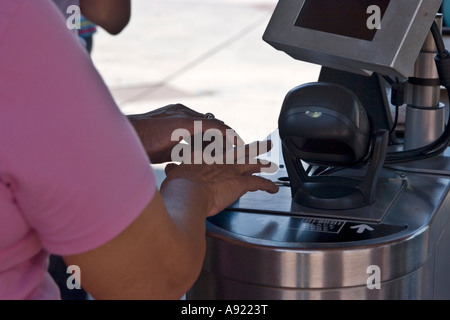 A tourist places her fingertip at a biometrics scanning machine at Universal Studios Orlando Stock Photo