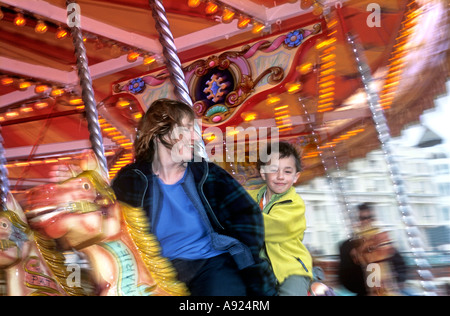 Mother and son on a merry-go-round, Brighton seafront, East Sussex. Stock Photo