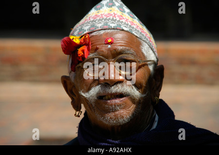 Portrait Newari man with traditional hat and flower on his forehead wearing glasses Bhaktapur Nepal Stock Photo