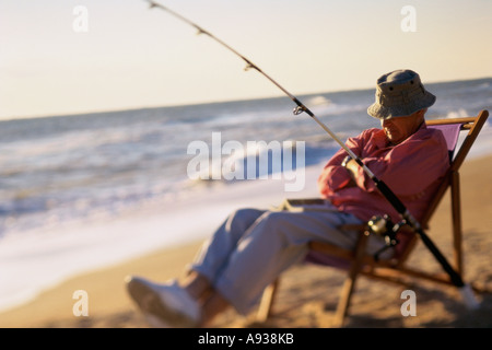 Boy Sitting On Chair On Beach Fishing With Makeshift Rod High-Res