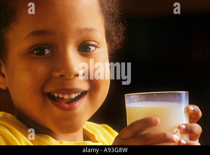 Infant girl enjoying a glass of milk in her home kitchen Stock Photo