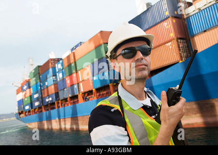 Man wearing hard hat using walkie-talkie at container terminal Stock Photo