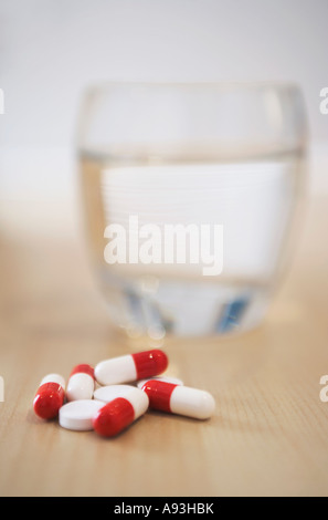 Pile of pills and glass of water on table, close-up Stock Photo