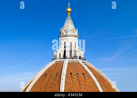 Horizontal close up of tourists at the very top of the Duomo against a bright blue sky. Stock Photo