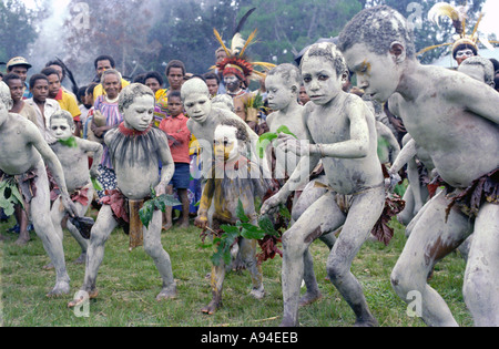 Children dancing as Asaro mudmen Asaroka Eastern Highlands Province Papua New Guinea Stock Photo