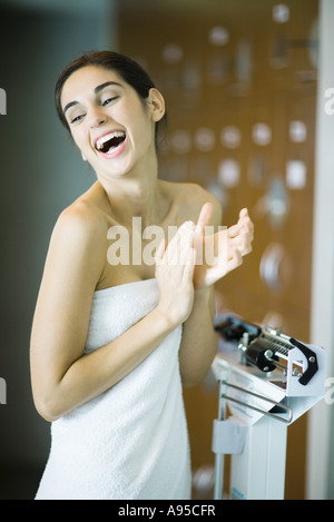 Young woman standing on scale, laughing Stock Photo