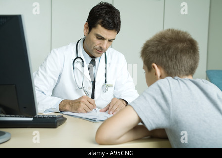 Doctor sitting across from child patient, taking notes Stock Photo