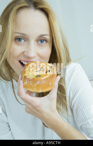 Woman eating pastry, smiling at camera Stock Photo