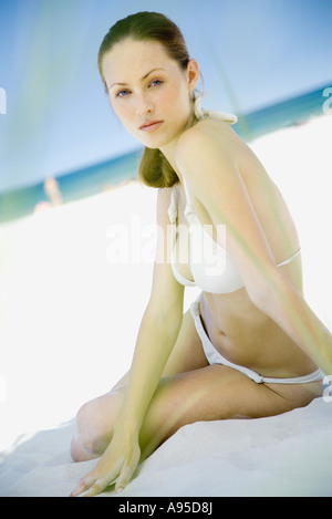 Woman wearing bikini, sitting on sand at beach Stock Photo