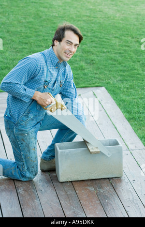 Man sawing piece of wood Stock Photo