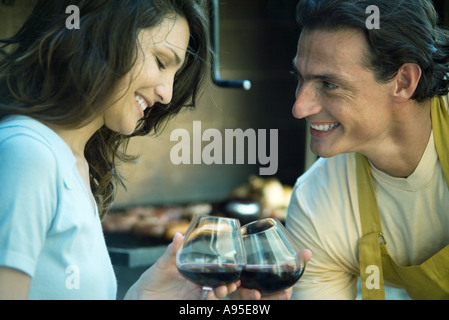 Couple clinking glasses of wine in front of grilling food Stock Photo