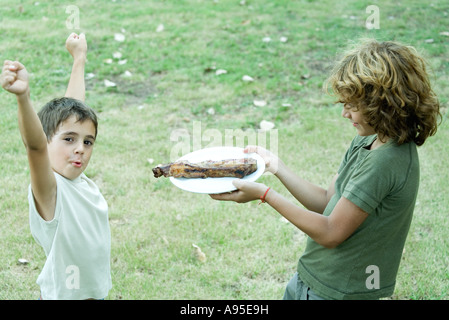 Boy handing friend plate of grilled meat Stock Photo