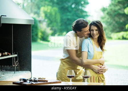 Couple having cookout, man hugging woman from behind Stock Photo