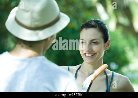 Couple standing face to face outdoors, one holding up hot dog Stock Photo