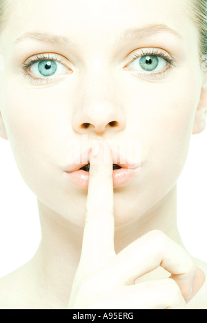 Teenage girl holding finger over lips, close-up, front view Stock Photo