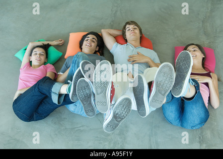 Teenage friends lying on floor with feet in the air, view from directly above Stock Photo