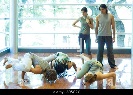 Young adults doing crow pose in yoga class Stock Photo