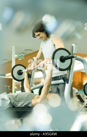 Man lifting barbell while second man spots Stock Photo