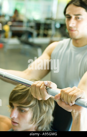 Man lifting barbell while second man spots Stock Photo