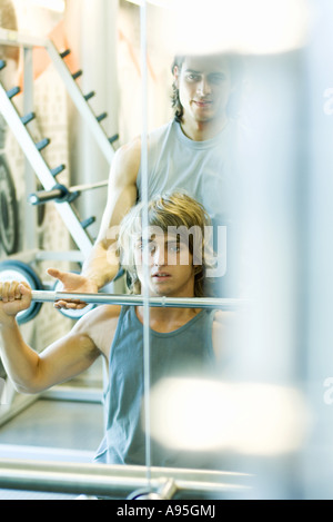 Man lifting barbell while second man spots Stock Photo