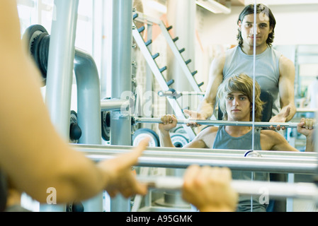 Man lifting barbell while second man spots Stock Photo