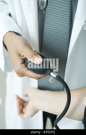 Doctor taking woman's blood pressure, close-up Stock Photo