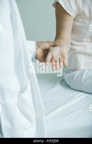 Doctor taking woman's pulse, close-up Stock Photo