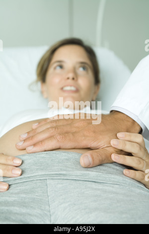 Pregnant woman lying on back, doctor's hand on stomach Stock Photo