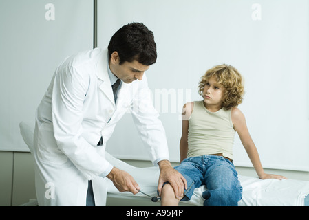 Doctor checking boy's reflexes Stock Photo