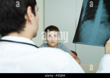 Doctor sitting across from boy, holding up x-ray Stock Photo