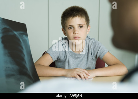 Doctor sitting across from boy, looking at x-ray Stock Photo