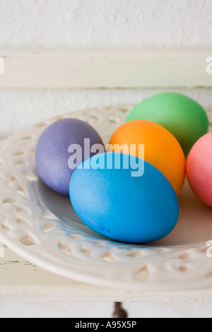 Easter eggs on porcelain plate on wooden shelf Stock Photo