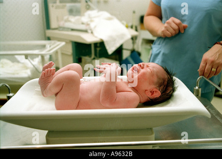 Newborn baby being weighed by midwife after birth Stock Photo