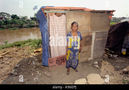 Jakarta slum area 1997. Lady poses outside her makeshift home by a polluted river which regularly floods due to the fact that Jakarta is sinking. Stock Photo